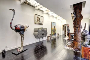 Vue traversante d’un loft à Paris 17 – Sculptures contemporaines, fresques animales et mobilier artistique dans un espace lumineux à la décoration éclectique.