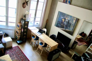 Coin salle à manger sous lumière naturelle, avec œuvre contemporaine en fond et mobilier design, dans un intérieur typiquement parisien.