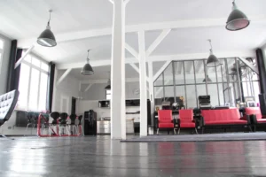 Vue large sur un loft parisien à l’esprit atelier, avec verrière industrielle, mobilier design rouge et coin salle à manger, situé rue du Faubourg Saint-Denis dans le 10ᵉ arrondissement.