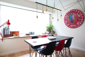 Salle à manger lumineuse avec grande fenêtre, table design et décoration éclectique dans un loft à Paris 15.