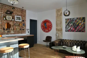 Salon au style industriel dans un appartement à Montmartre les Abbesses Paris 18, avec mur en briques, œuvres d’art contemporain, canapé Chesterfield et parquet bois chaleureux.