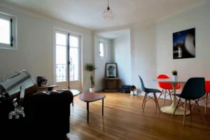Séjour lumineux avec parquet d'origine, coin repas design et décoration contemporaine – appartement à vendre à Paris 19ᵉ, quartier Belleville.