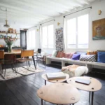 Coin salon cosy avec lumière naturelle, poutres apparentes et tables basses design