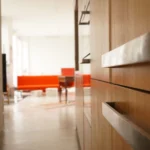 Vue de la cuisine aux lignes épurées en bois clair avec perspective sur le séjour, dans un loft design à Paris 10.