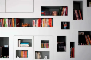 Gros plan sur les niches murales avec livres et objets déco dans le séjour.