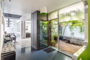 Entrée contemporaine ouvrant sur une terrasse végétalisée, avec espace repas extérieur et vue sur les pièces à vivre.