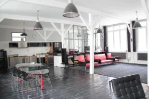 Grand loft lumineux avec cuisine ouverte en inox, salle à manger vitrée, parquet noirci et salon rétro dans un esprit industriel, Paris 10ᵉ, quartier Faubourg Saint-Denis.