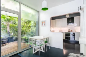 Cuisine ouverte avec coin repas, donnant sur une terrasse arborée dans un cadre calme et verdoyant à Paris 18.