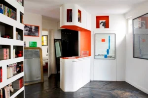 Entrée avec placard sur mesure, détails orange et lignes graphiques.