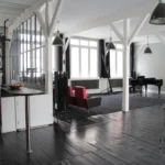 Loft lumineux à Paris 10 avec verrière atelier, poutres apparentes, parquet noir et piano à queue dans un espace de vie élégant, proche de la Gare de l’Est.