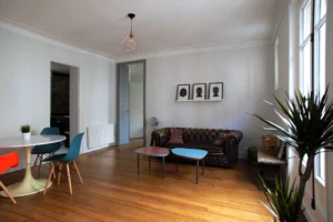 Salon avec parquet ancien, canapé Chesterfield et décoration éclectique – appartement lumineux à vendre à Belleville, Paris 19ᵉ.