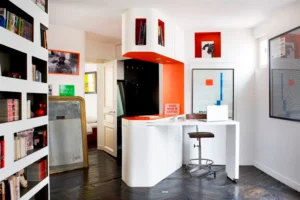 Coin bureau dans l’entrée, mobilier intégré blanc et orange vif.