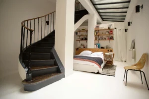 Chambre en mezzanine avec escalier en bois noir et rangements intégrés