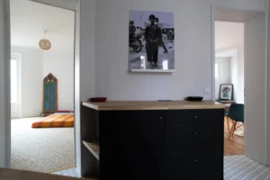 Espace central distribuant la chambre et le séjour, avec meuble de rangement et décoration murale – appartement à vendre à Belleville, Paris 19ᵉ.