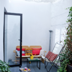 Petite terrasse urbaine avec salon d’extérieur, végétation et lumière naturelle, dans un loft situé rue du Faubourg Saint-Denis à Paris 10ᵉ.