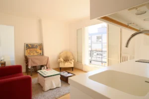 Vue depuis la cuisine sur le salon lumineux avec accès au balcon, Paris 17ᵉ – quartier rue de Lévis.