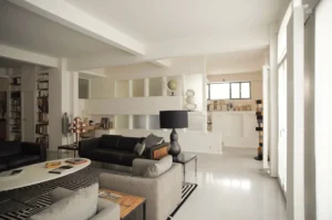 Vue traversante sur le séjour design avec salon et coin bureau, dans un appartement lumineux à vendre à Paris 10ᵉ, rue Martel.