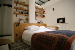 Chambre parentale sous verrière avec tête de lit en bois clair et déco contemporaine