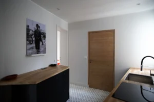 Cuisine aménagée avec plan de travail en bois, évier encastré et décoration murale contemporaine – appartement à vendre à Paris 19ᵉ, quartier Belleville.