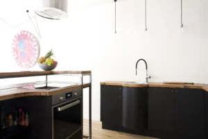 Cuisine originale avec plan de travail arrondi, robinetterie noire et éclairage suspendu dans une maison à Paris 15.