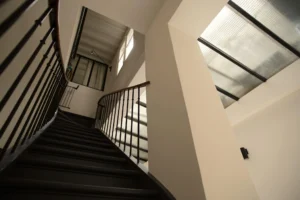Escalier intérieur à rambarde noire, sous verrière, typique d’un loft parisien industriel