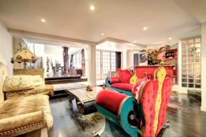 Vue sur l’espace de vie du loft à Paris 17 – Canapés colorés, bar rouge, décoration éclectique et ouverture sur la salle à manger artistique.