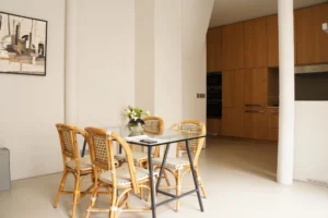 Salle à manger avec table en verre et mobilier en rotin dans un loft à Paris 10ᵉ