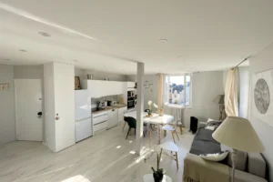 Pièce de vie lumineuse avec cuisine ouverte, coin salle à manger et salon dans un appartement duplex à vendre à Deauville.