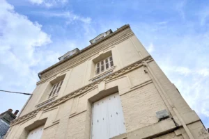 Façade de l’immeuble en briques claires à Trouville-sur-Mer, vue en contre-plongée avec ciel bleu.
