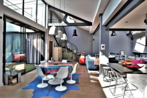 Loft lumineux à Nanterre avec verrière, salle à manger design, charpente apparente et volumes ouverts sur l’extérieur.