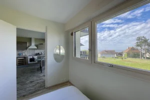 Vue depuis la chambre sur la cuisine ouverte et la mer, dans un appartement lumineux à Benerville-sur-Mer.