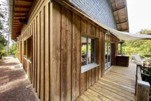 Terrasse en bois longeant la maison avec ouvertures vitrées sur jardin