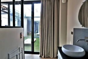 Salle d’eau élégante avec vasque et vue sur le patio intérieur, dans un loft lumineux à Nanterre.