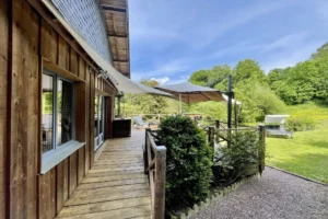 Vue sur terrasse en bois orientée plein sud, entourée de verdure