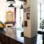 Cuisine ouverte baignée de lumière naturelle, avec plan en béton, miroirs et vue dégagée, dans un appartement à Belleville – Paris 19ᵉ.