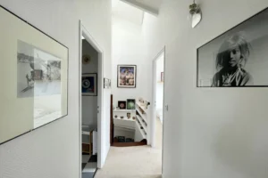 Palier lumineux d’un appartement en duplex à Honfleur, avec bibliothèque intégrée et décoration artistique.