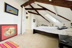 Chambre sous pente avec poutres apparentes et coin lecture, dans un appartement à vendre à Honfleur.