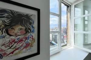 Fenêtre ouverte avec vue sur les toits et le Vieux Bassin de Honfleur, dans un appartement à vendre en plein centre historique.