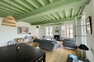 Pièce de vie spacieuse avec fenêtres en enfilade, parquet et mobilier chaleureux dans un appartement à vendre à Honfleur Quality Street Immobilier