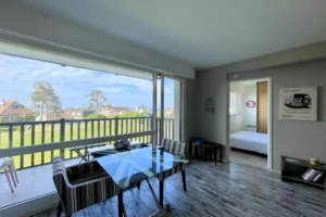 Séjour lumineux avec parquet et baie vitrée offrant une vue dégagée sur la mer à Benerville-sur-Mer.
