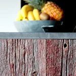Gros plan sur des planches en bois brut patiné et une corbeille de fruits exotiques dans une cuisine au style authentique à Belleville – Paris 19ᵉ.