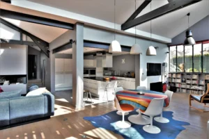 Cuisine ouverte contemporaine dans un loft à Nanterre, avec verrière atelier, grande table colorée et ambiance design.