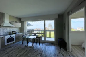 Cuisine ouverte moderne avec coin repas et grande baie vitrée sur vue mer à Benerville-sur-Mer.