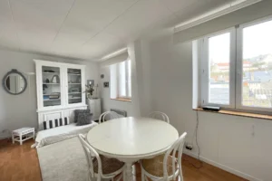 Salle à manger et buffet vitré dans une ambiance blanche et bois, vue dégagée sur les toits.