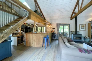 Séjour lumineux avec cuisine ouverte en bois et poutres apparentes