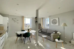 Séjour lumineux avec coin repas, canapé et décoration sobre dans un appartement duplex à vendre à Deauville.