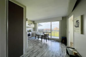 Vue d’ensemble de la pièce de vie avec cuisine ouverte, salle à manger et accès à la terrasse vue mer à Benerville-sur-Mer.