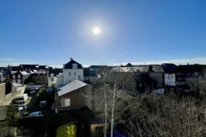 Vue dégagée sur les toits de Deauville et la mer sous un ciel ensoleillé, depuis un appartement en duplex.