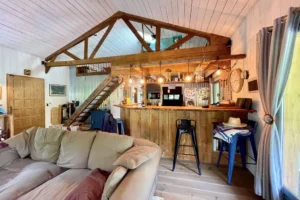 Espace cuisine et salon avec plafond cathédrale et escalier en bois brut