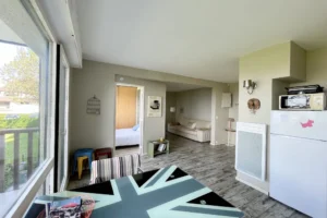 Vue sur l’espace salon et l’entrée de la chambre depuis la salle à manger dans un appartement à Benerville-sur-Mer.